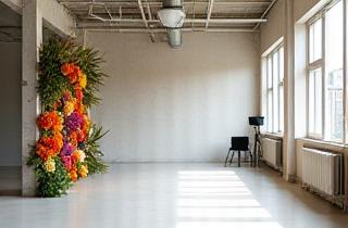 Intérieur d'un studio photo lumineux avec de grandes fenêtres et un arrière-plan floral.